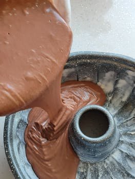 Close-up of chocolate cake batter being poured into a bundt pan, ready for baking.