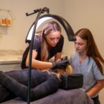 Women performing a cosmetic procedure in a modern dermatology clinic. Focus on precision and care.